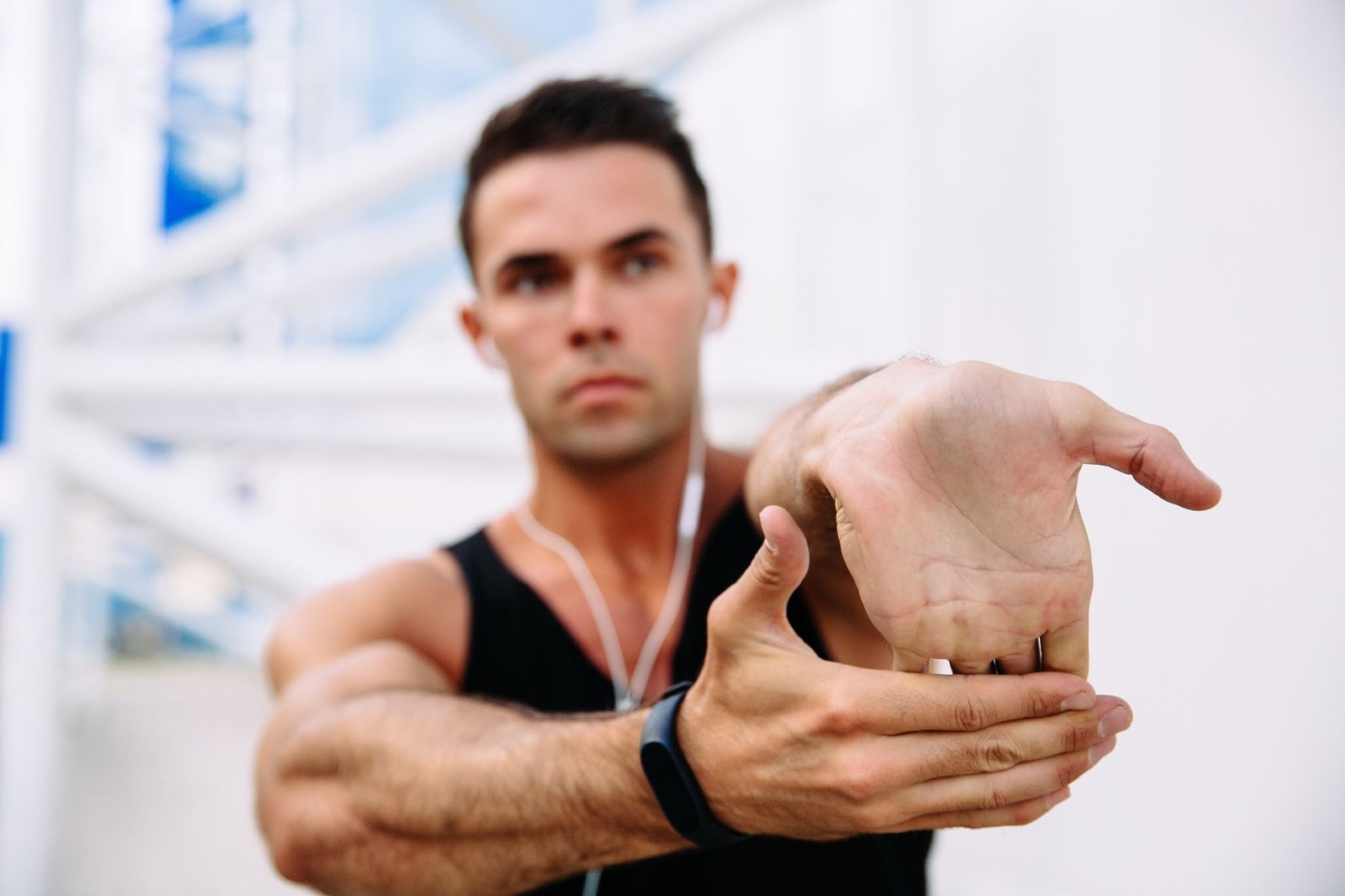 athlete male earphones while stretching his arms preparing workout outdoors