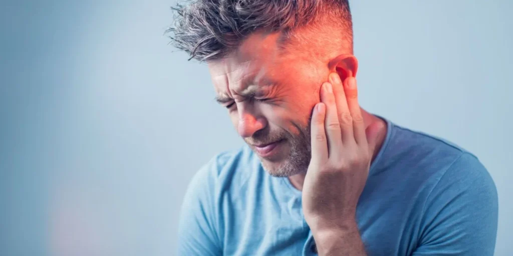 TMJ & Migraines: Connection & Relief Options person touching their jaw and temple area to indicate facial tension.